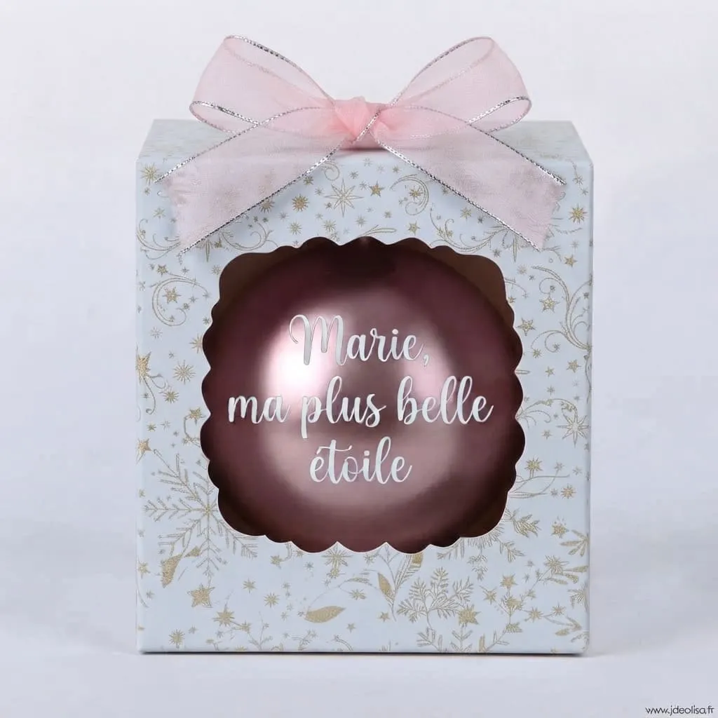 boule-de-noel-marie-ma-plus-belle-etoile Boîte cadeau blanche à motifs dorés et étoilés avec un nœud rose, contenant une boule de Noël rose nacrée avec l'inscription "Marie, ma plus belle étoile".