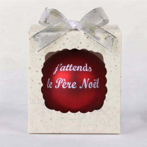 Boîte cadeau avec un nœud argenté contenant une boule de Noël rouge brillante avec l'inscription J'attends le Père Noël