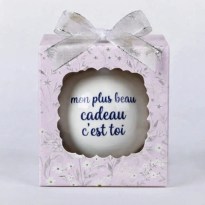 Boîte cadeau violette/lilas à motifs floraux blancs et argentés avec un nœud argenté, contenant une boule de Noël blanche avec le texte bleu "mon plus beau cadeau c'est toi".