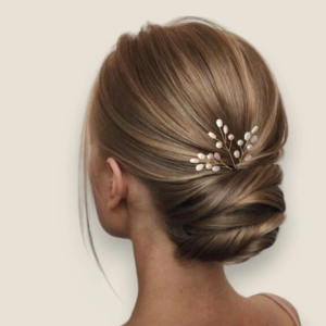 Coiffure de mariage avec chignon bas orné d'un bijou de cheveux mariée aux perles nacrées et fils dorés.