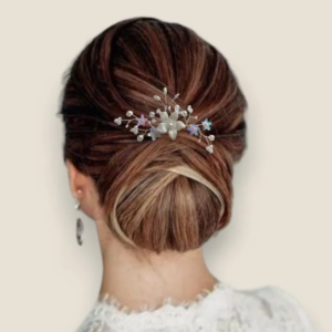 Peigne de mariage argenté avec perles nacrées et cristaux porté sur un chignon bas de mariée.