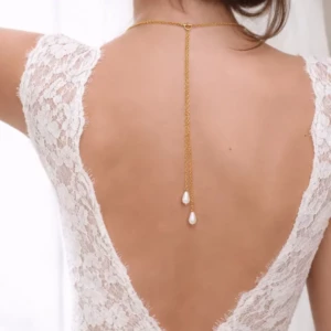 Collier de dos fin en chaîne dorée avec deux perles en goutte d'eau porté sur une robe de mariée en dentelle à dos nu