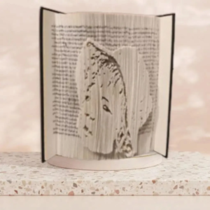 Objet de décoration artisanal en livre plié représentant un portrait de visage vu de profil, posé sur un support en marbre.