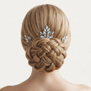 Coiffure de mariée élégante avec un chignon bas tressé, sublimé par un ensemble de trois épingles à cheveux décorées de feuilles ou de cristaux effet opale