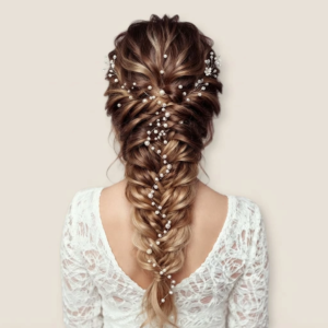 Longue tresse de mariée sophistiquée et texturée, embellie par une longue vigne de cheveux délicate parsemée de perles blanches