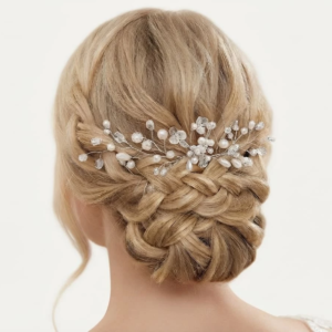 Coiffure de mariée élégante mettant en valeur un chignon bas tressé, agrémenté d'un peigne ou d'une vigne de cheveux argentée ornée de perles et de cristaux étincelants.