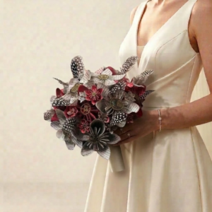 Bouquet de mariée vintage en origami bordeaux et papier imprimé de pages de livre orné de plumes tachetées.