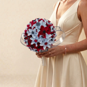 Bouquet de mariée original sur le thème du cinéma en origami rouge et blanc entouré d'un ruban en forme de pellicule de film.