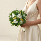 Bouquet de mariée chic et végétal composé de pivoines blanches, denses feuillages verts et feuilles dorées scintillantes.