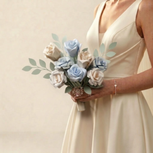 Bouquet de mariée délicat composé de roses en papier bleu ciel et ivoire avec feuillage vert sauge et bijou broche.