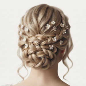 Vue de dos d'une coiffure de mariée sophistiquée sur cheveux blonds avec tresses et chignon tressé, agrémentée de multiples petits pics à cheveux de mariage IdeaLisa en forme de fleurs nacrées.